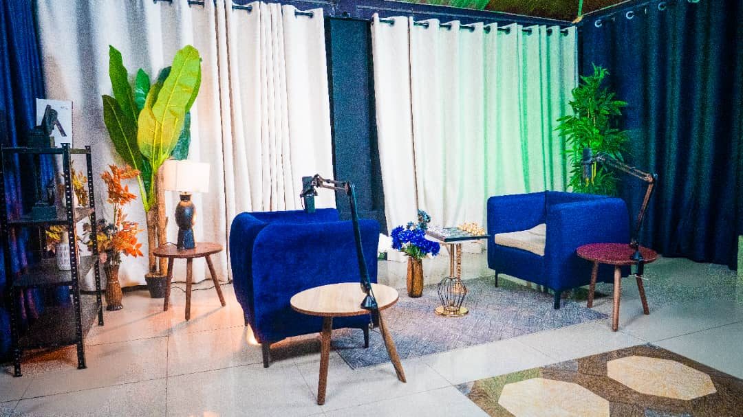 Setup podcast avec fauteuils bleus, rideaux et plantes