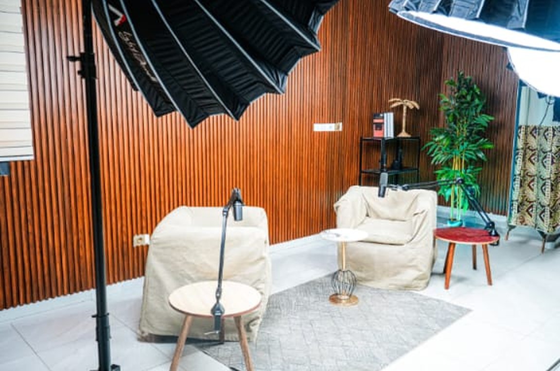 Setup podcast devant le mur en bois, fauteuils beiges et éclairage studio