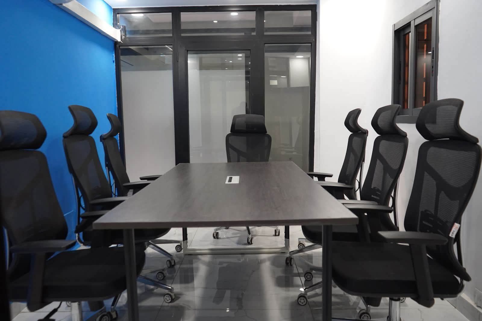 Salle de réunion : grande table, fauteuils ergonomiques noirs, cloison vitrée